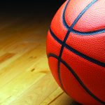 A large basketball in the shadow of the court